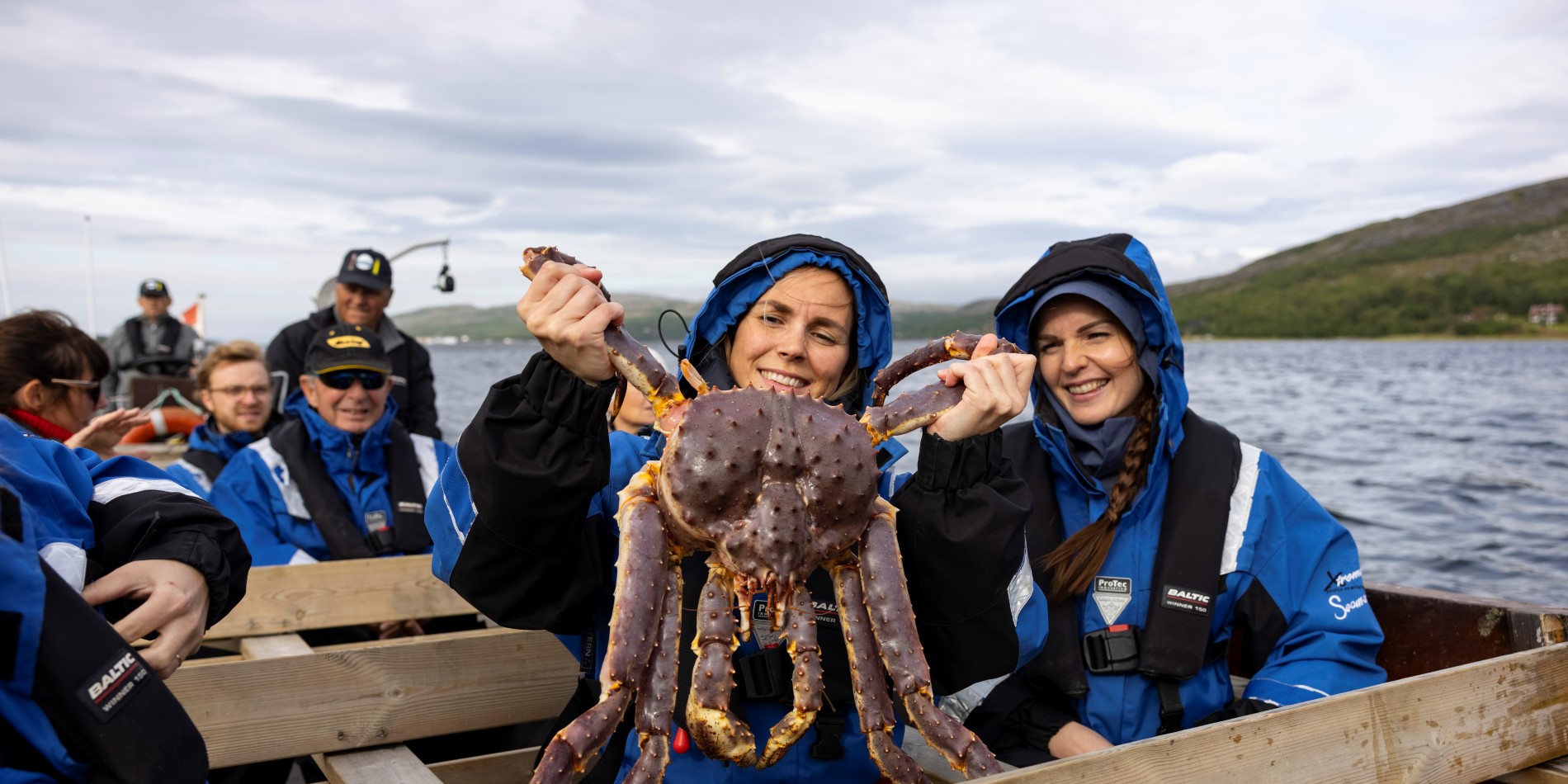 A girl holding a large king crab onboard during a king crab safari in northern Norway