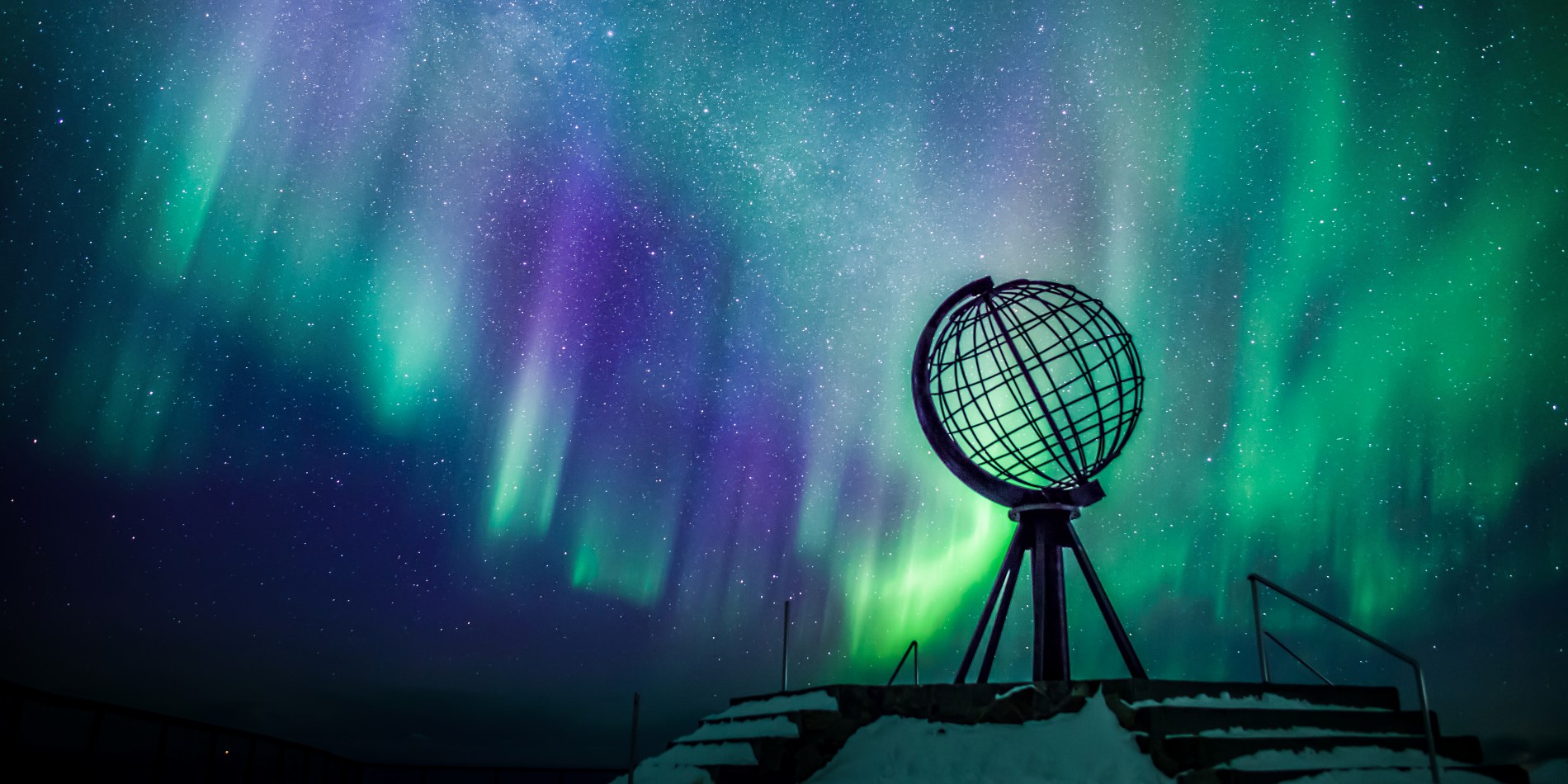 The globe statue on The North Cape surrounded by northern lights