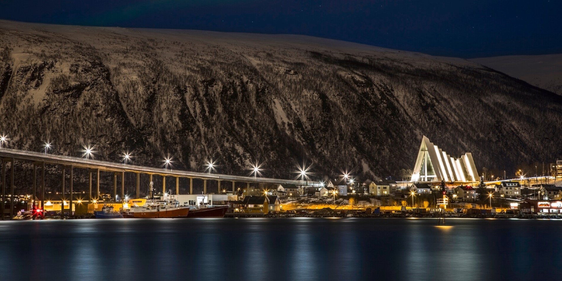 The Arctic Cathedral seen from Tromsøya, Norway. The bridge and cathedral light up the dark night.