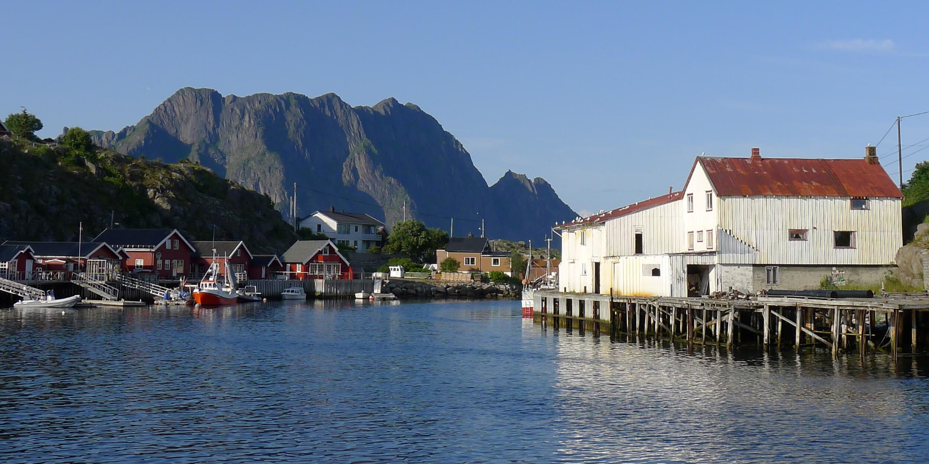 A boat is docked next to a body of water with Lofoten in the background